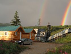 A double rainbow behind the cabins and gold dredge at the Chicken Gold Camp - Chicken, Alaska